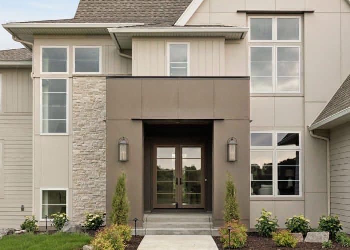 Modern two-story home entrance with landscaped lawn and gabled roof