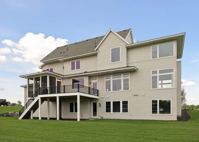 Large three-story suburban house with raised deck and lawn
