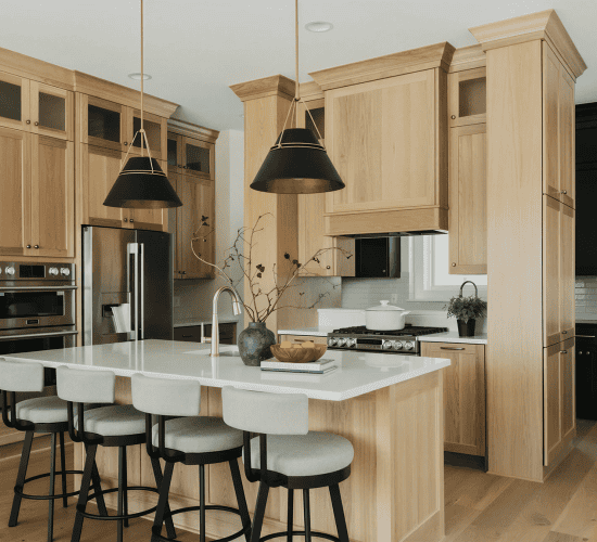 Modern kitchen with wood cabinets, island, stools, and pendant lights