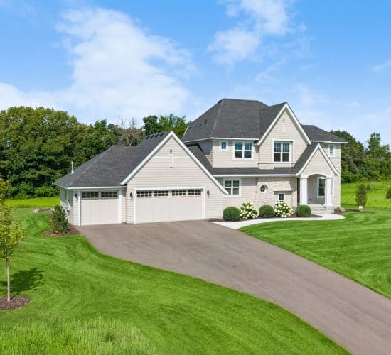 Angled front view of a custom home with curved driveway and landscaped lawn