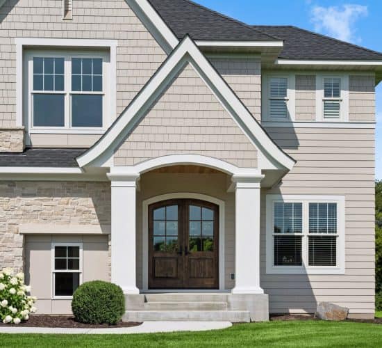 Arched front entrance with wood double doors and stone exterior accents