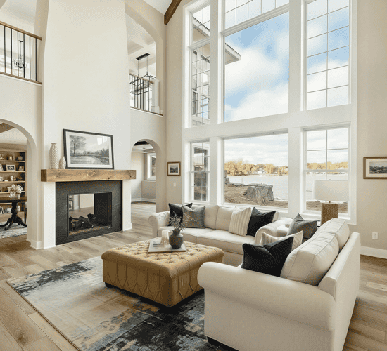 Bright double-height living room with fireplace and waterfront views