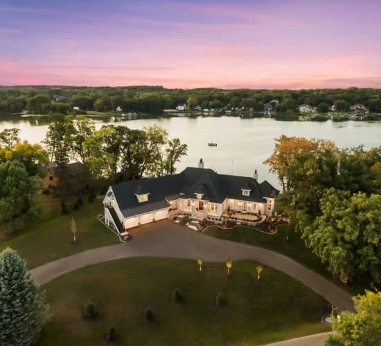 Lakeside home with curved driveway at sunset