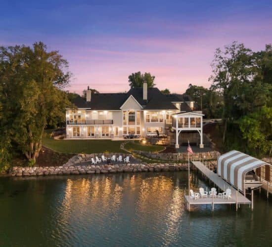 Waterfront home at dusk with dock and covered boat lift