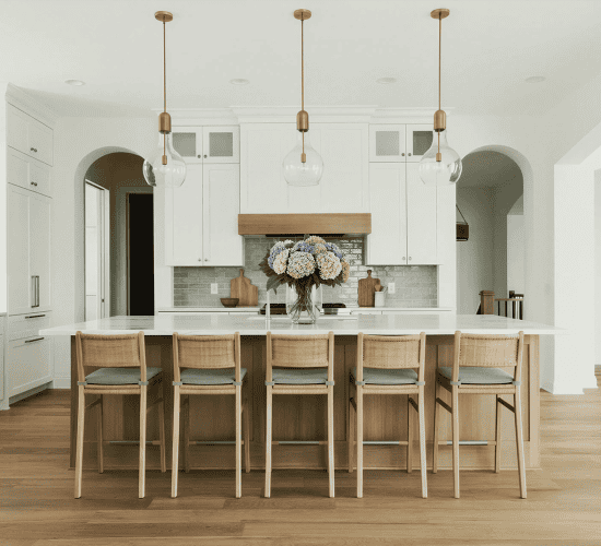 Bright white kitchen with island, six stools, and pendant lights
