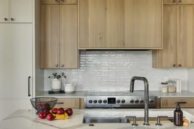 Modern kitchen with wood cabinets, marble island, and stainless stove