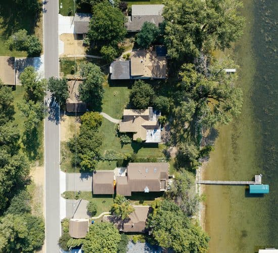 Aerial view of lakeside homes, road, trees, and dock