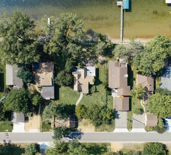 Aerial view of lakeside homes, trees, docks, and street