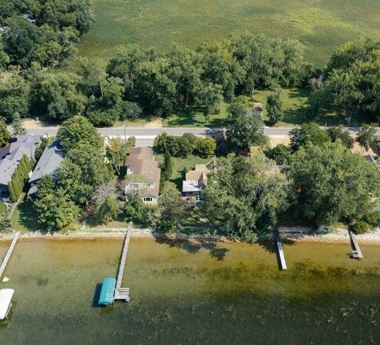 Aerial view of lakeside homes, docks, and dense trees