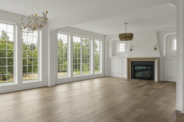 Bright empty living room with fireplace and tall windows