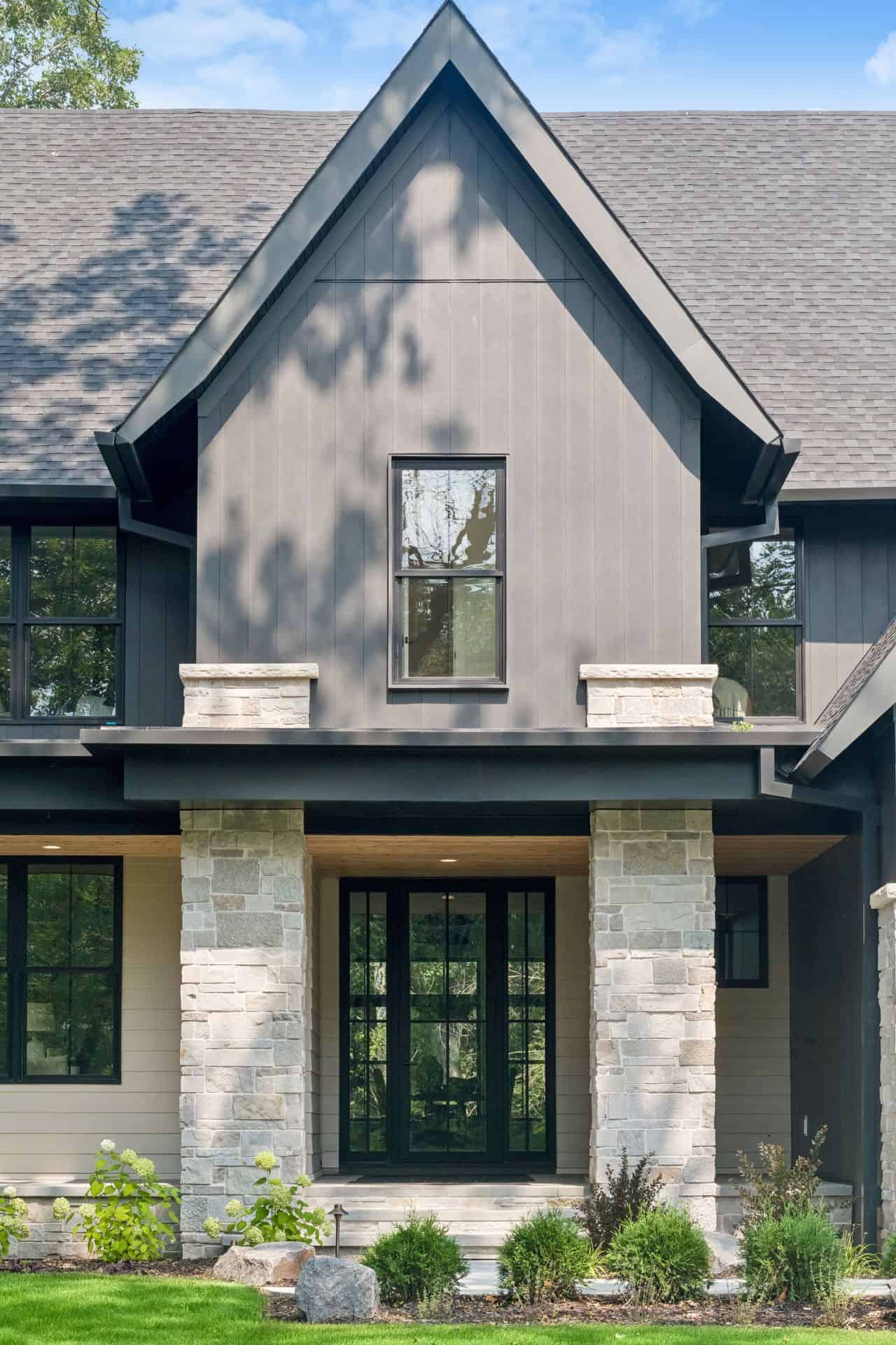 Modern gray home entrance with stone columns and black doors