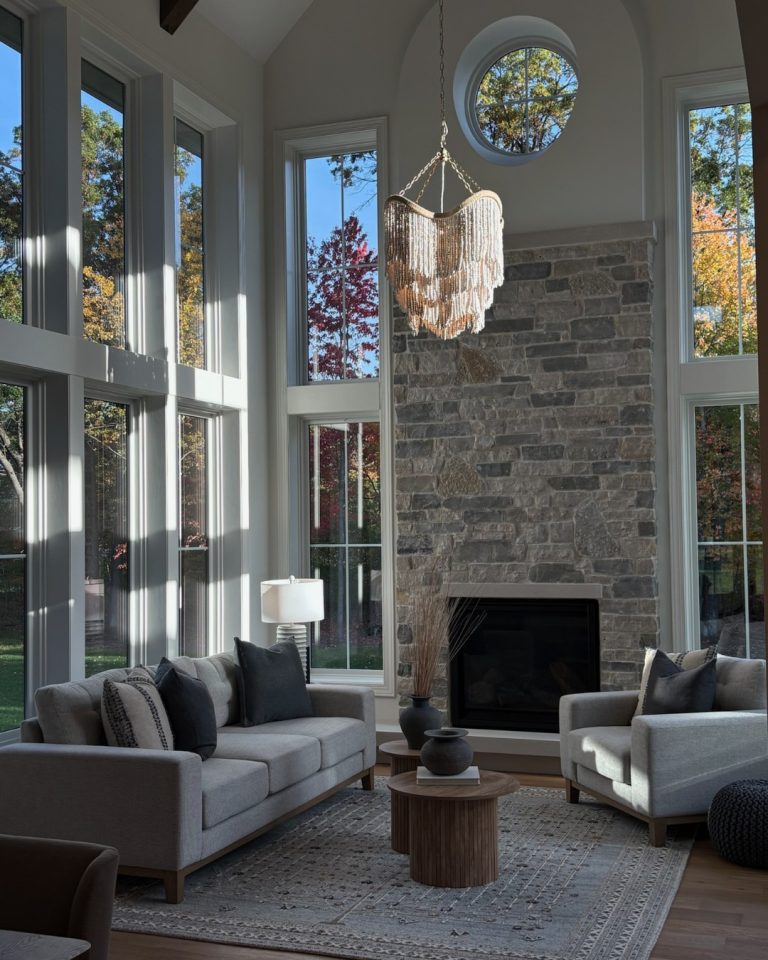 Elegant living room with large windows, stone fireplace, and modern decor.