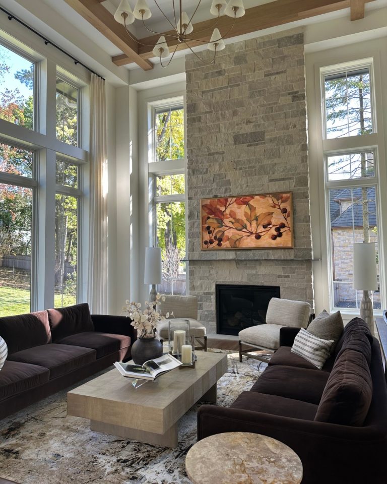 Elegant living room with large windows, stone fireplace, and modern furniture.