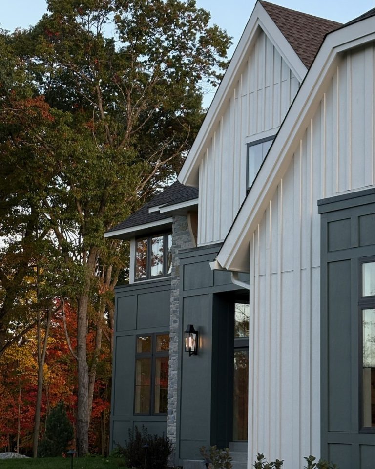 Modern farmhouse exterior with white and dark gray siding and large windows.