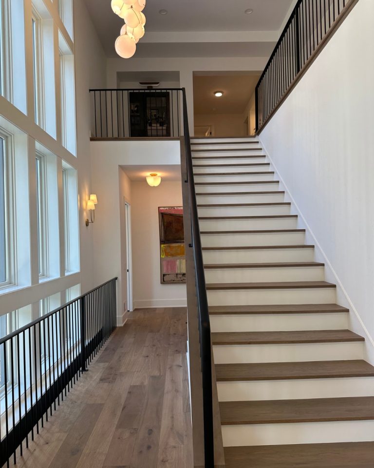 Modern staircase with black railing and large windows in a contemporary home.